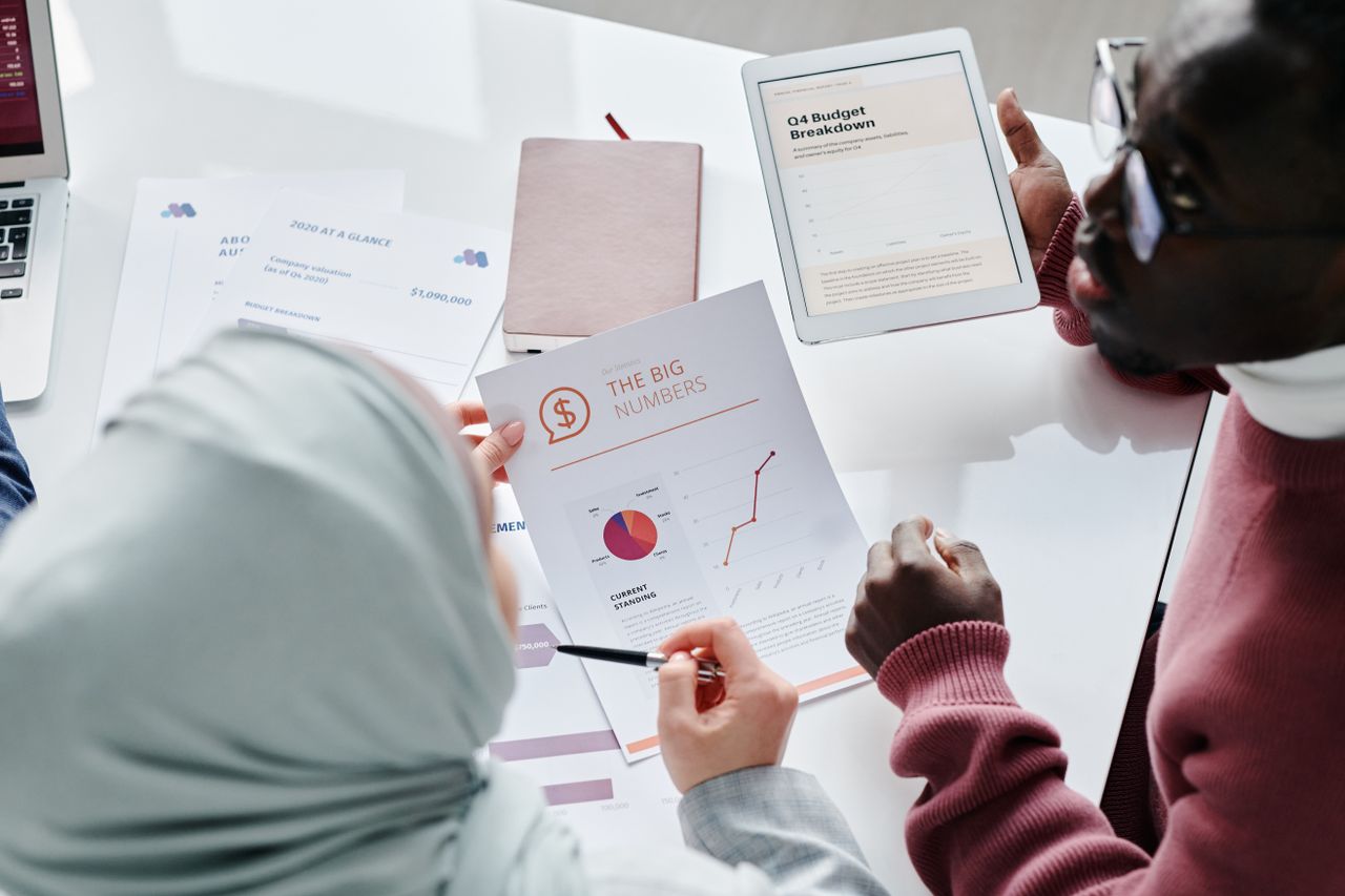 Deux professionnels examinent des rapports financiers, des graphiques et une ventilation budgétaire