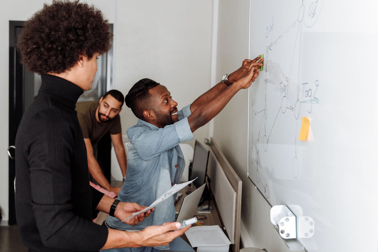 Des participants échangent et développent des idées ensemble devant un tableau blanc